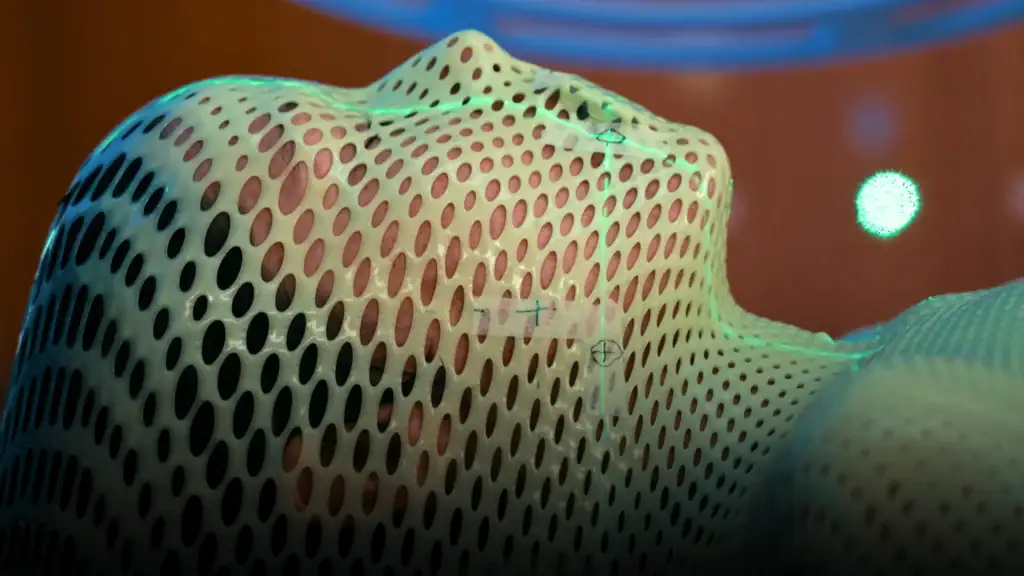 Woman under a mesh mask getting ready for radiotherapy